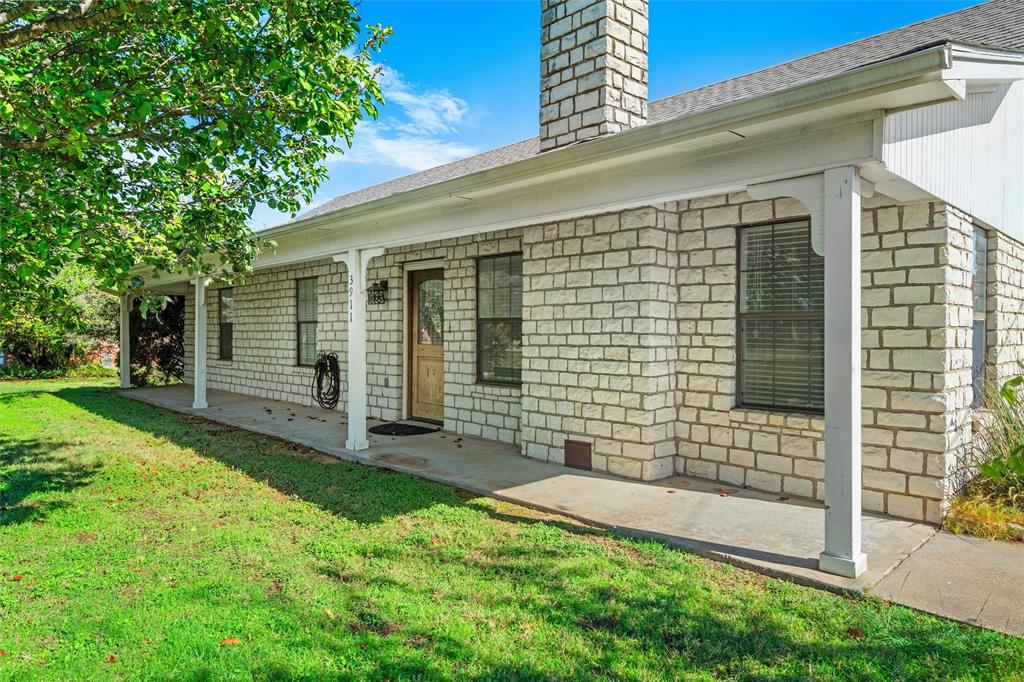 Exterior facade featuring stone veneer masonry, a covered porch with white columns, a prominent stone chimney, and dark-framed windows