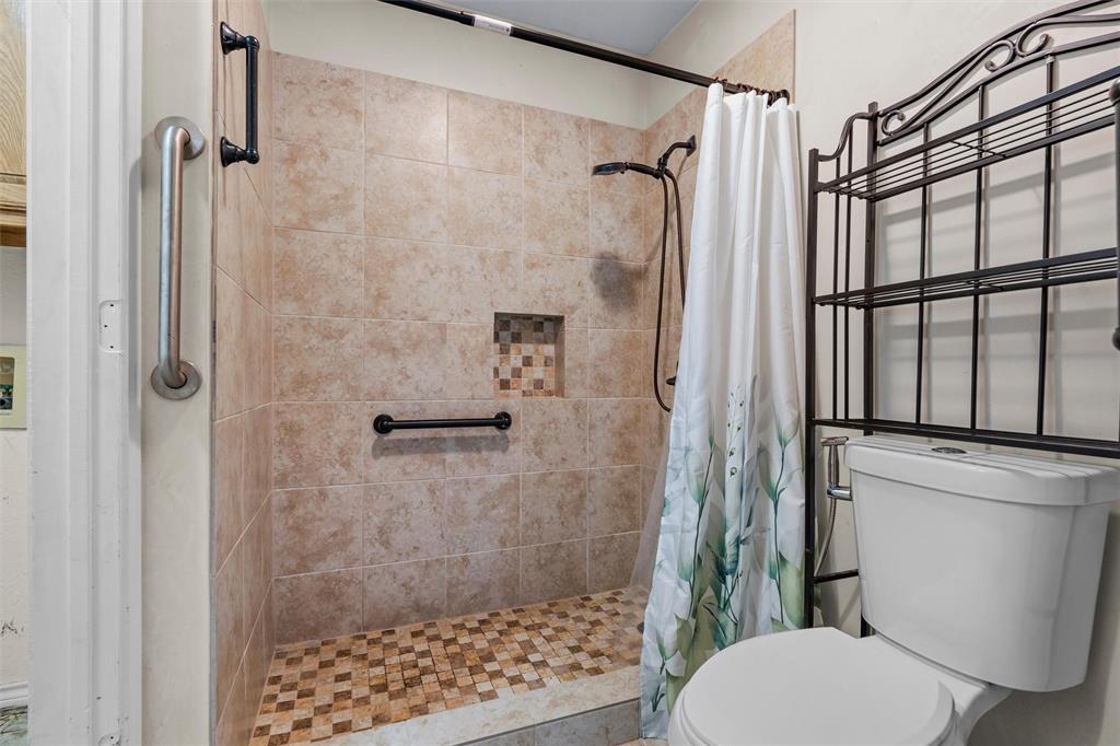 Walk-in shower featuring neutral tile walls, a mosaic tile floor, an integrated wall niche, and oil-rubbed bronze hardware