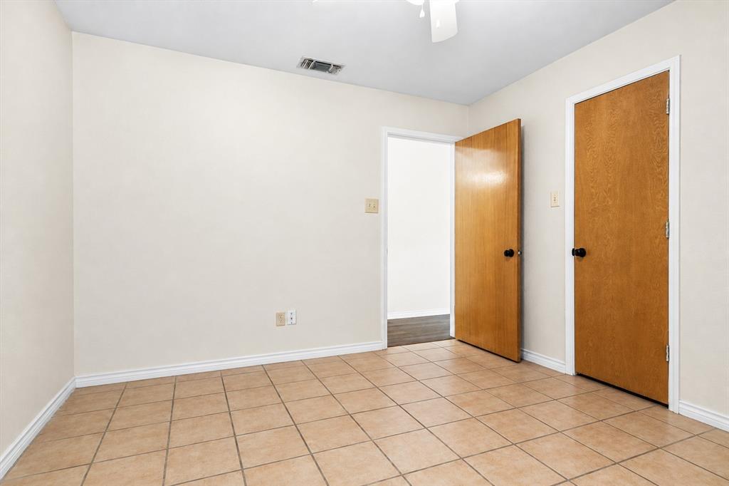 Neutral-toned interior space featuring ceramic tile flooring, solid wood-finish doors with matte black hardware, and a ceiling-mounted light fixture