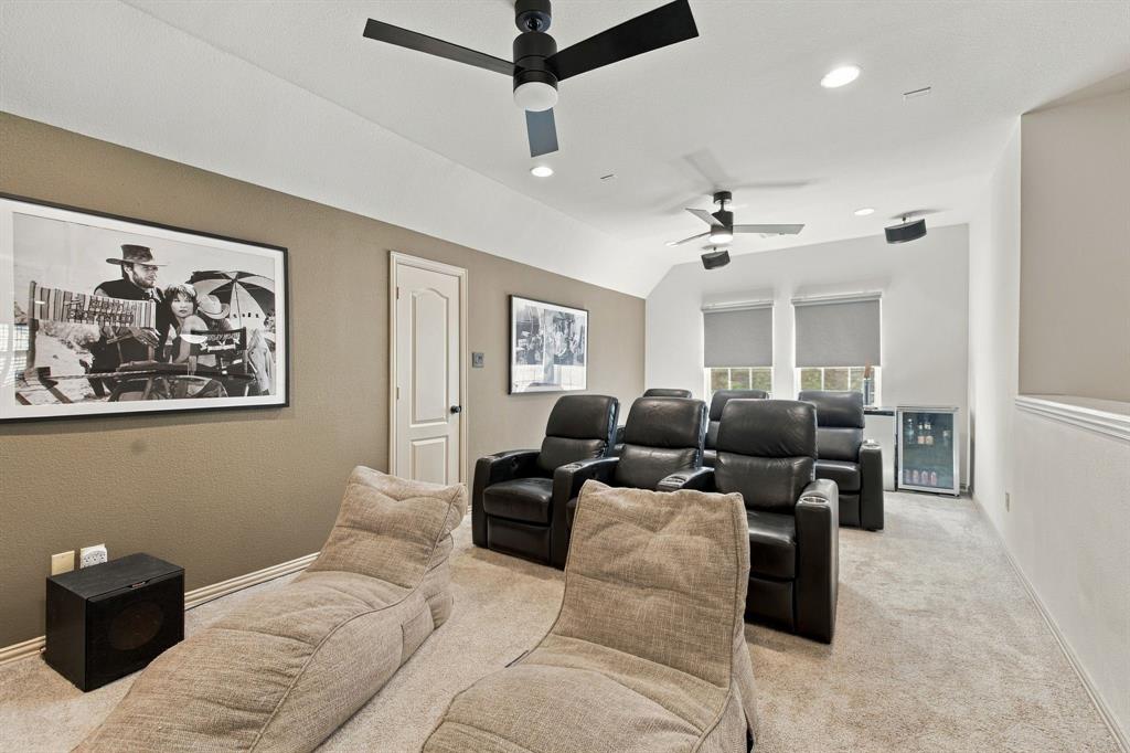 Multi-purpose room featuring dual ceiling fans, recessed lighting, integrated wall-mounted speakers, and a built-in beverage refrigerator