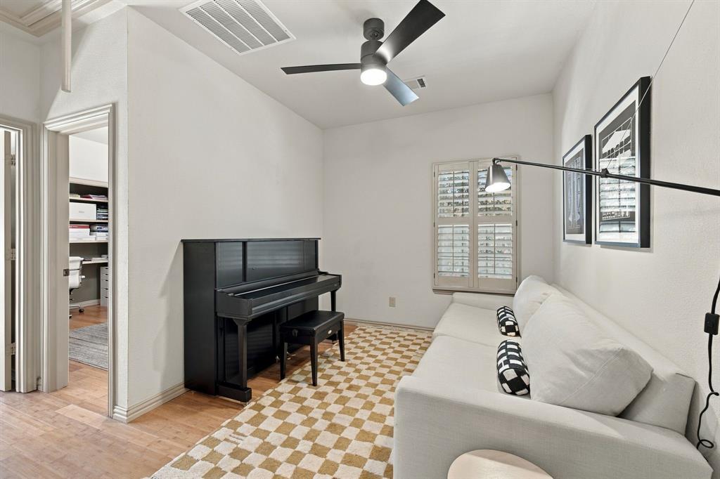 Interior room featuring wood-finish flooring, a matte black ceiling fan with integrated lighting, and plantation shutters