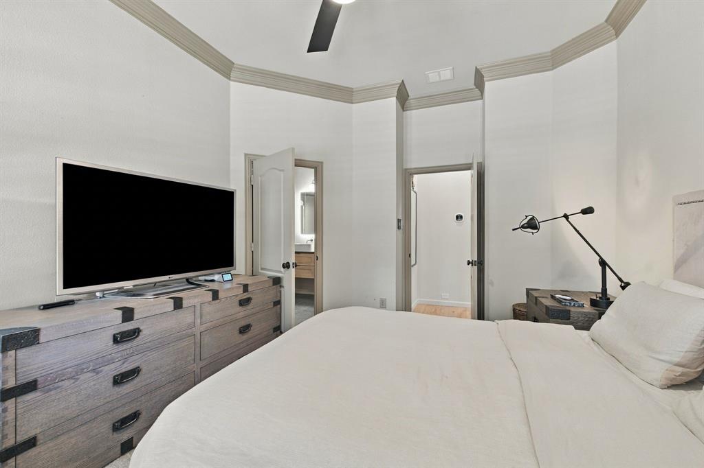 Bedroom featuring a tray ceiling with crown molding and an integrated ceiling fan