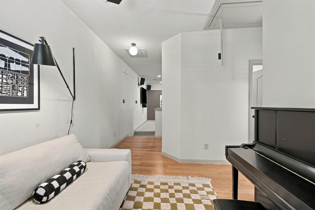 Interior hallway featuring wood-finish flooring, white walls, and a wall-mounted matte black swing-arm lamp