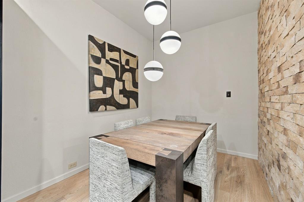 Textured stone accent wall paired with wood-finish flooring and three-tiered spherical pendant lighting