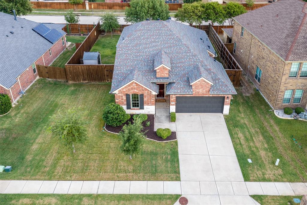 Brick exterior featuring a multi-gabled roofline, front-facing two-car garage, concrete driveway, and landscaped front yard