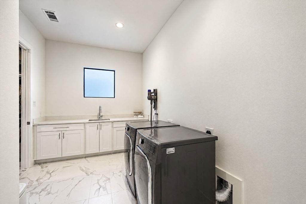 A spacious laundry room includes lower cabinetry for detergent storage and room to fold without feeling cramped