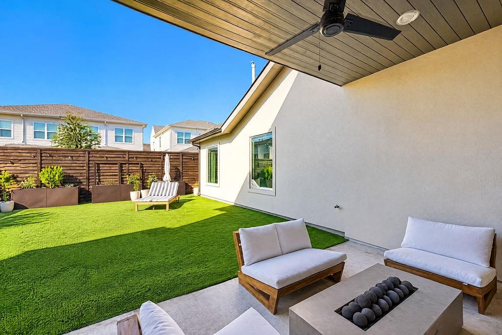 Stackable sliding glass doors pull back to connect the indoor living room directly to a covered outdoor patio fitted with a ceiling fan
