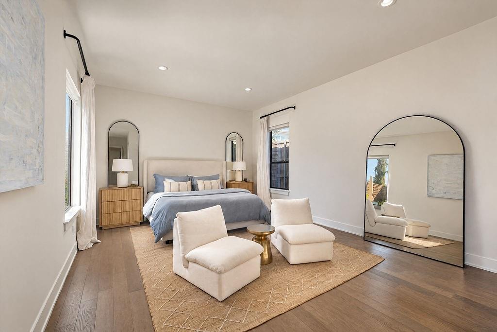 The main-floor primary suite offers room for a king bed and a cozy reading chair, wrapped in rich hardwood flooring