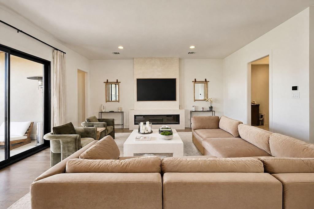 Unwind in a light-filled living space with an electric fireplace built into the feature wall for cozy evening relaxation