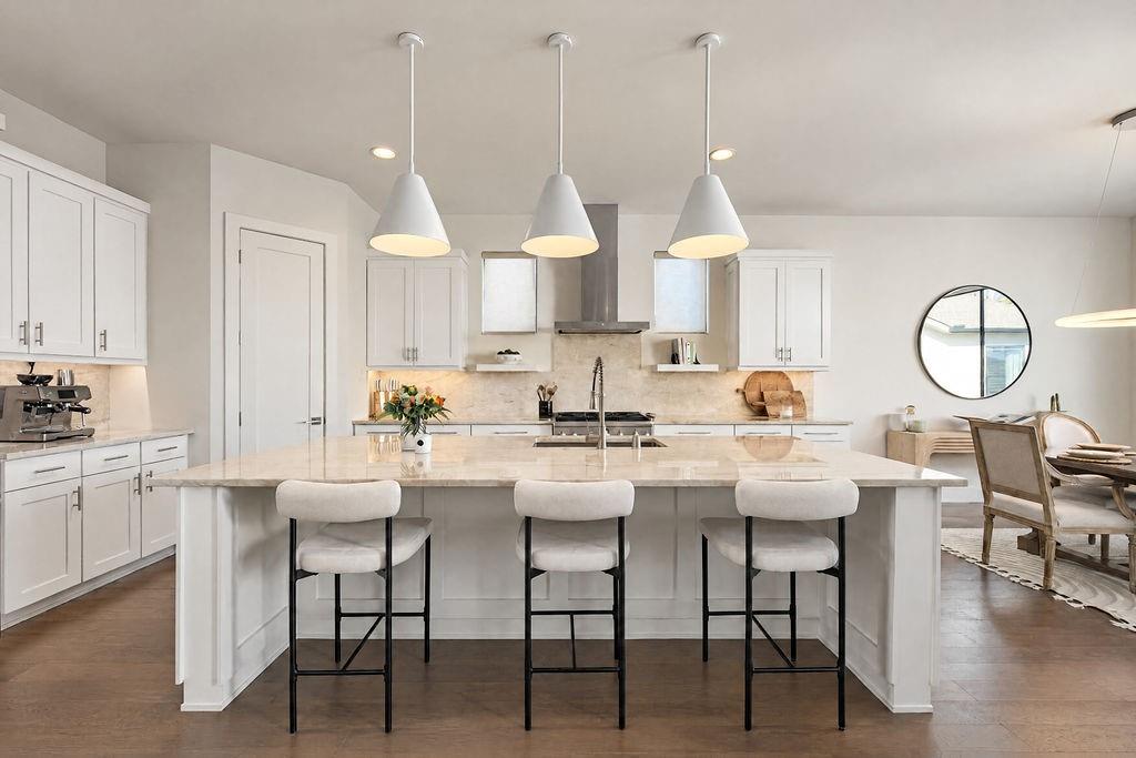 High-end pendant lights cast a soft glow over quartz countertops, pairing everyday practicality with effortless prep space