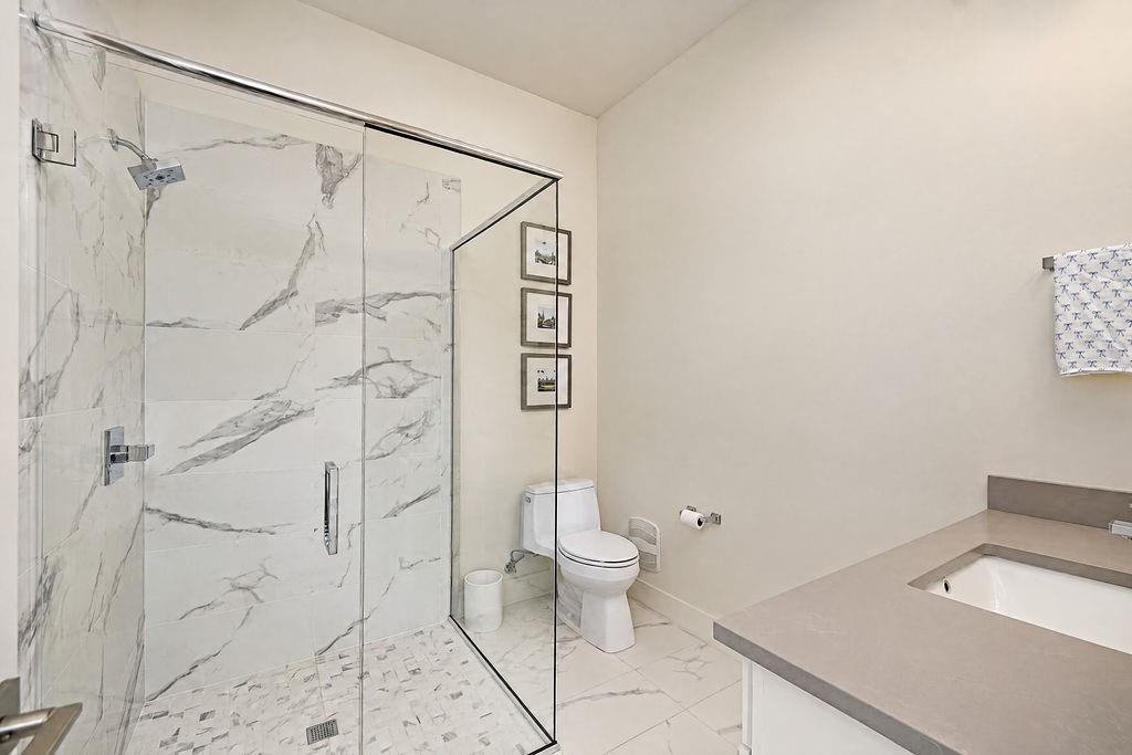 A full main-floor bathroom with a frameless glass shower and quartz vanity gives downstairs guests complete privacy
