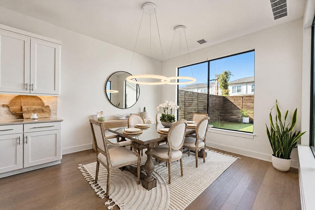 The dining area comfortably hosts dinner parties, positioned right under a custom chandelier with views out to the backyard