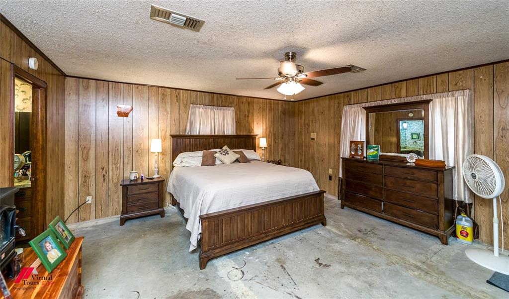 Wood-paneled interior walls, ceiling fan with integrated light fixture, and textured ceiling
