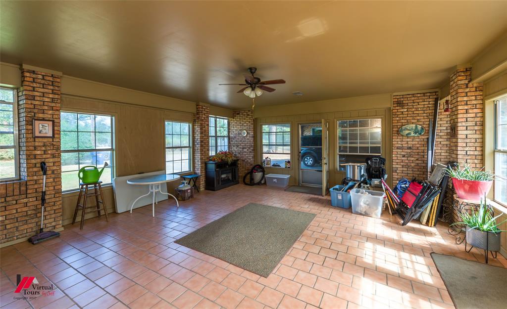 Enclosed patio featuring exposed brick columns, ceramic tile flooring, a ceiling fan with integrated lighting, and multiple windows