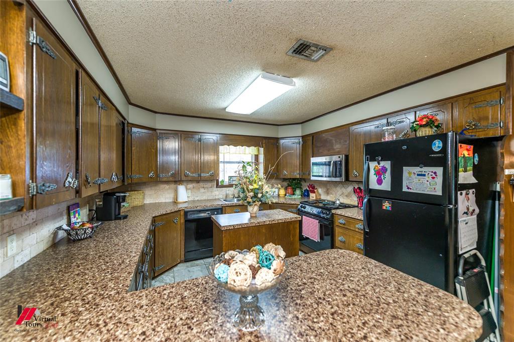 Kitchen featuring dark wood cabinetry, patterned stone-finish countertops, a central island, and stone-tiled backsplash