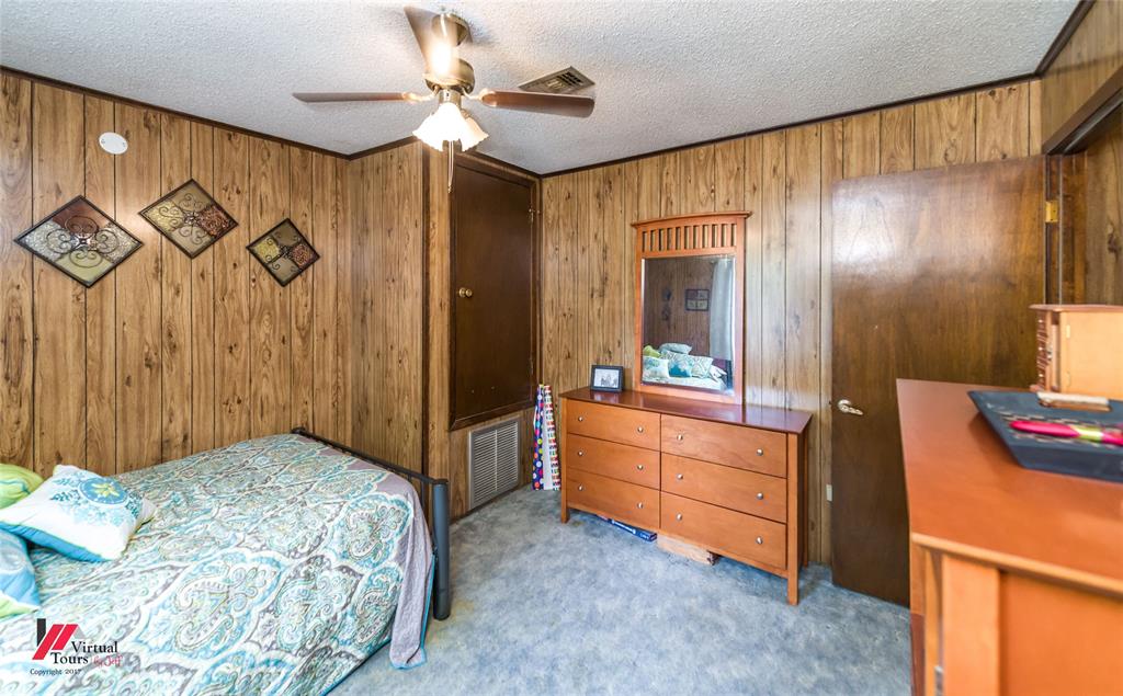Wood-paneled wall finishes, carpeted flooring, and ceiling-mounted fan with integrated light fixture