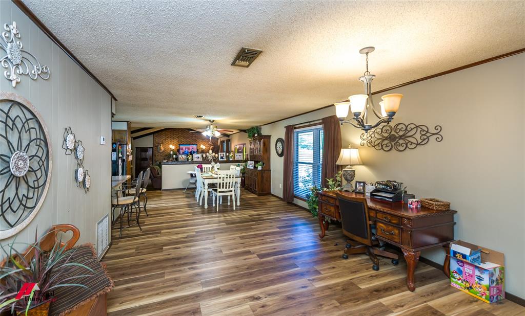 Open interior space featuring wood-finish flooring, a multi-arm chandelier with glass shades, and textured ceiling finish