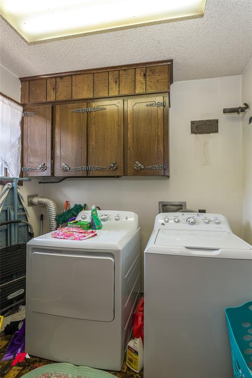 Laundry area featuring wood-finish wall-mounted cabinetry with decorative metal hardware and integrated overhead lighting