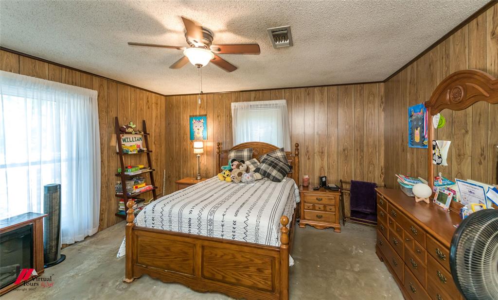 Interior space featuring wood-paneled walls, ceiling fan with integrated light fixture, and large window with vertical blinds
