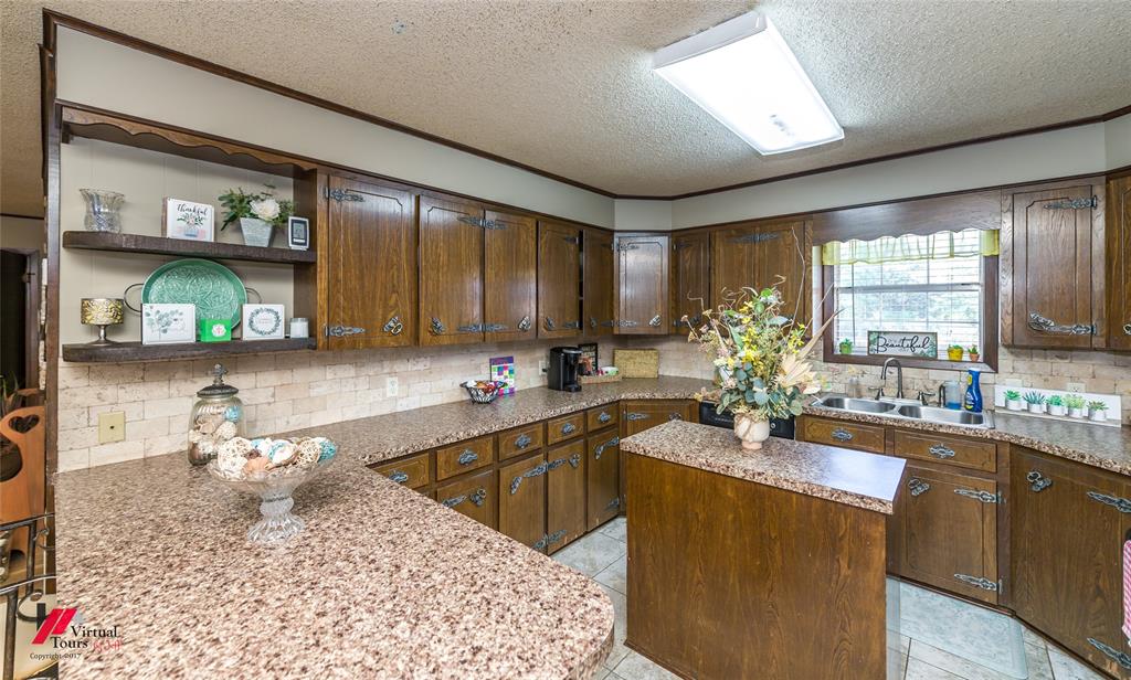 Kitchen featuring wood cabinetry, stone-finish countertops, tiled backsplash, center island, and built-in open shelving