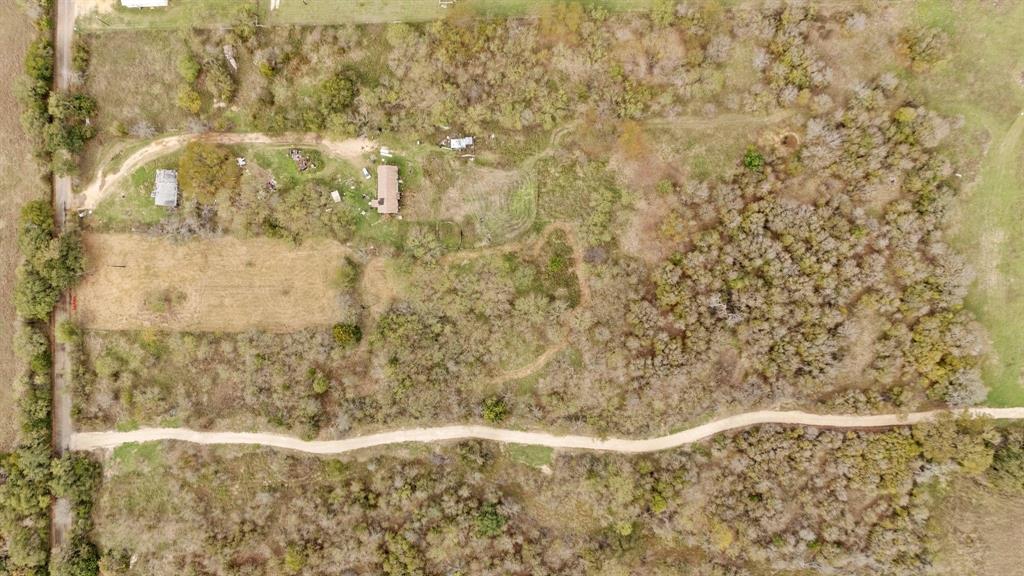 Aerial perspective featuring expansive acreage, dense woodland cover, a primary structure, and an unpaved access road Aerial perspective featuring expansive acreage, dense woodland cover, a primary structure, and an unpaved access road