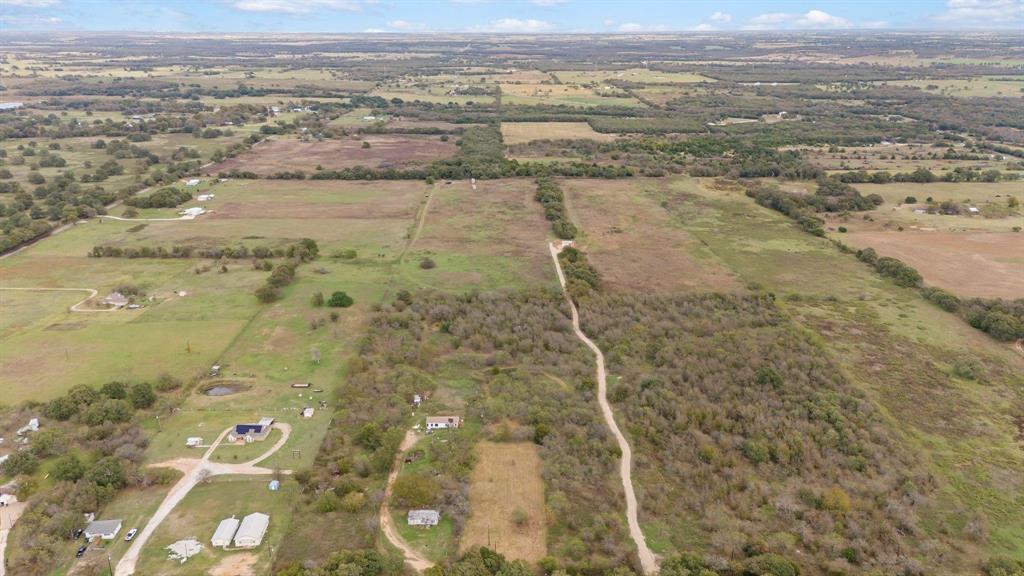 Expansive acreage featuring cleared pasture, areas of dense mature trees, and unpaved private access paths