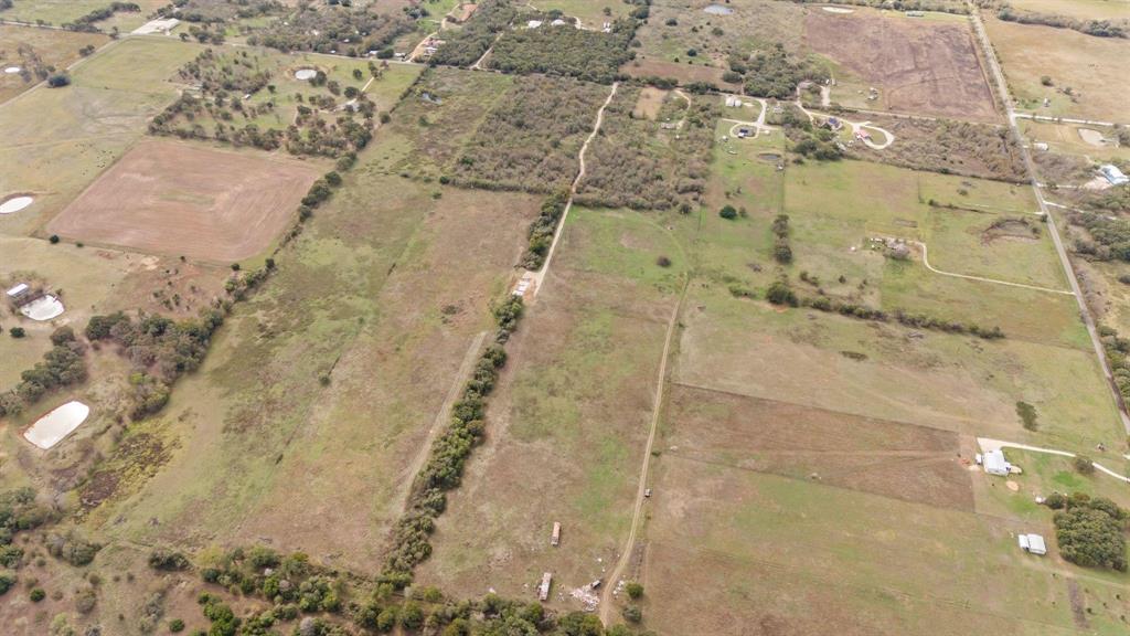 Expansive rural acreage featuring cleared pasture land, mature tree clusters, and established dirt access paths