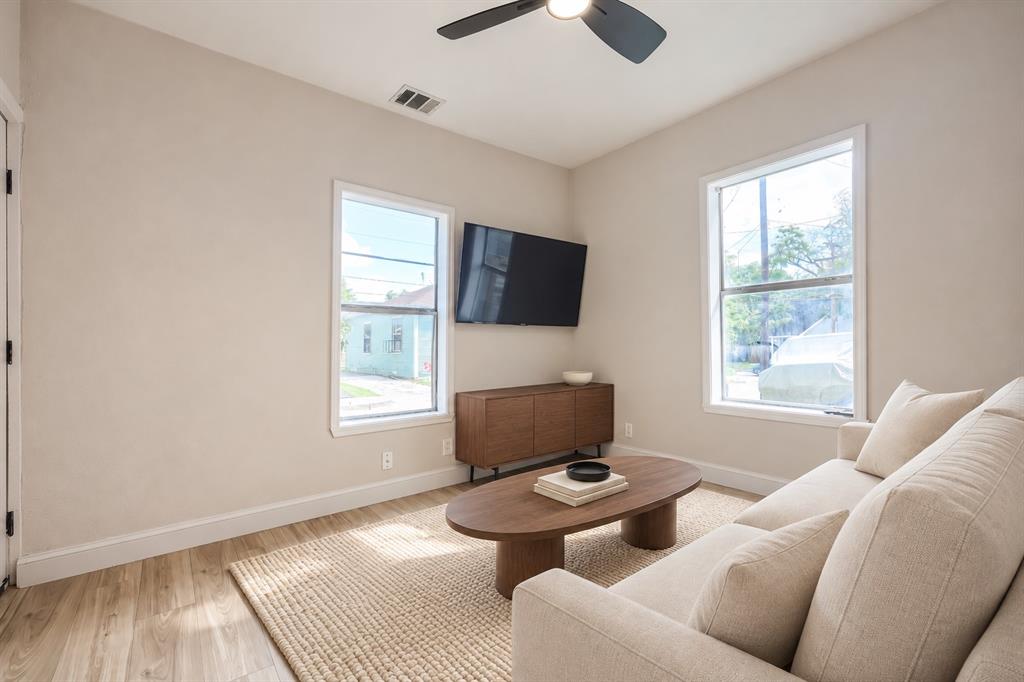 Neutral wall palette, wood-finish flooring, two large windows with crisp trim, and a ceiling fan