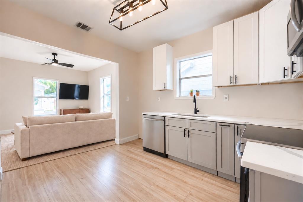 Kitchen featuring shaker-style cabinetry, white quartz countertops, stainless steel appliances, matte black hardware, and wood-finish flooring