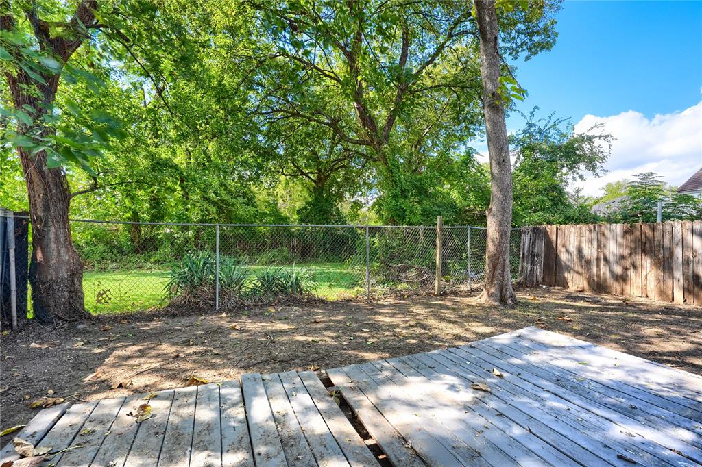 Backyard featuring a wood deck, chain-link fencing, and mature trees
