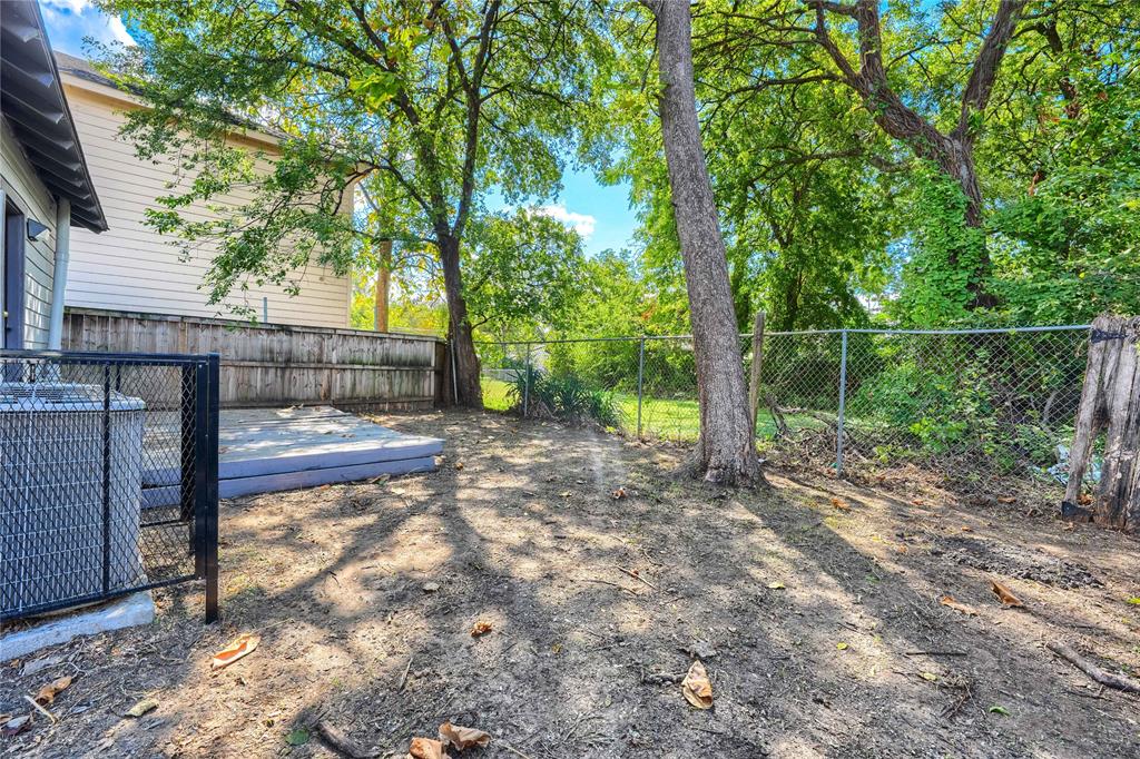 Outdoor space featuring a concrete patio, perimeter chain-link and wood fencing, and mature trees