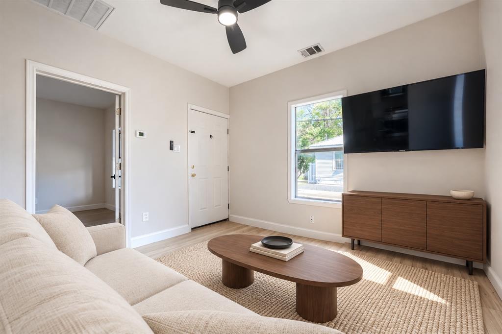 Neutral-toned interior featuring wood-finish flooring, a contemporary matte black ceiling fan, and a single-hung window with a white frame