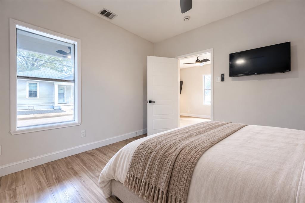Room interior featuring wood-finish flooring, a single-panel interior door with matte black hardware, and a ceiling fan