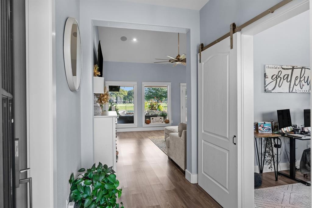 Entryway featuring wood-finish flooring, white paneled interior door, and a sliding barn-style door with metal track hardware Entryway featuring wood-finish flooring, white paneled interior door, and a sliding barn-style door with metal track hardware