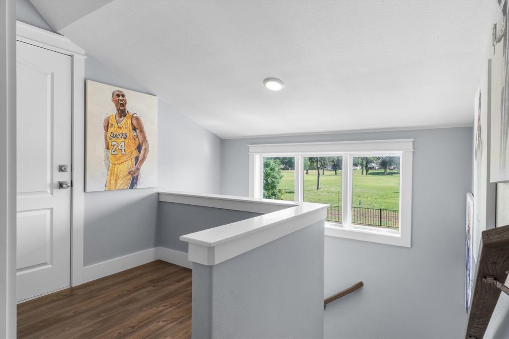 Landing area featuring wood-finish flooring, a vaulted ceiling with recessed lighting, and a multi-pane window with exterior landscape exposure