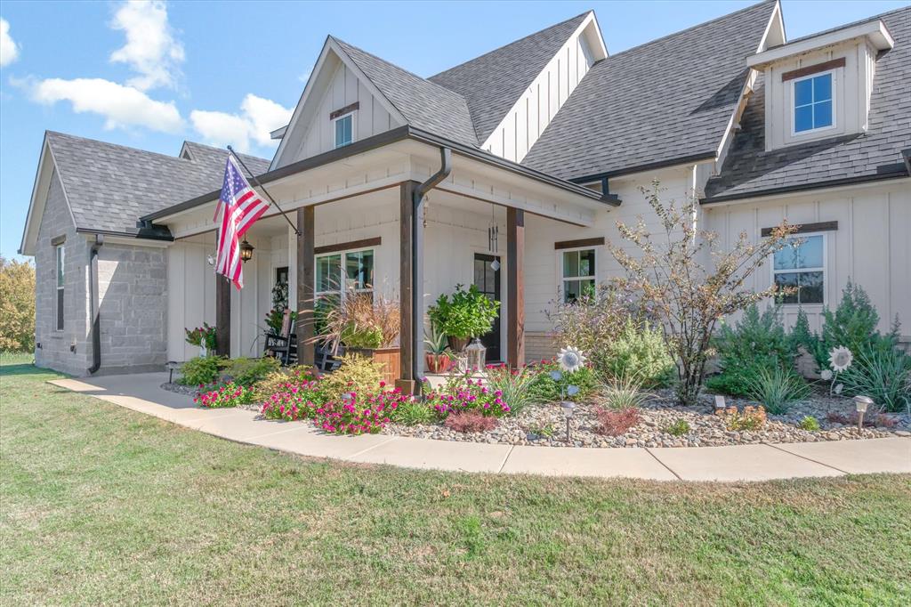 Modern farmhouse exterior featuring vertical board-and-batten siding, stone masonry accents, a covered front porch with timber-frame support columns, and multi-gabled rooflines Modern farmhouse exterior featuring vertical board-and-batten siding, stone masonry accents, a covered front porch with timber-frame support columns, and multi-gabled rooflines