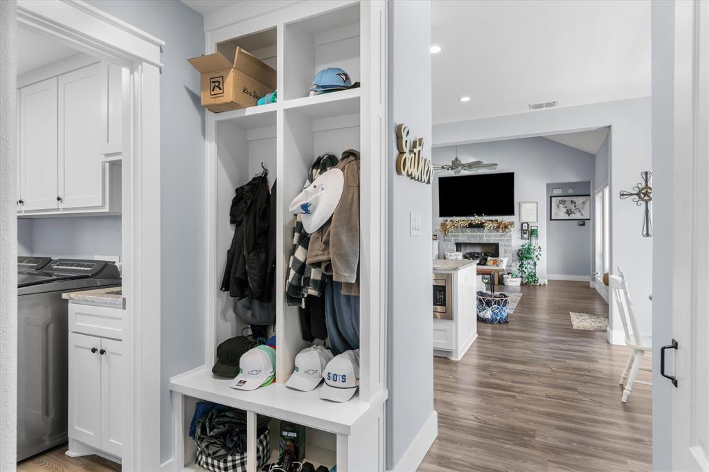 Custom built-in mudroom locker unit with shelving and bench seating, white cabinetry, wood-finish flooring, and recessed ceiling lighting