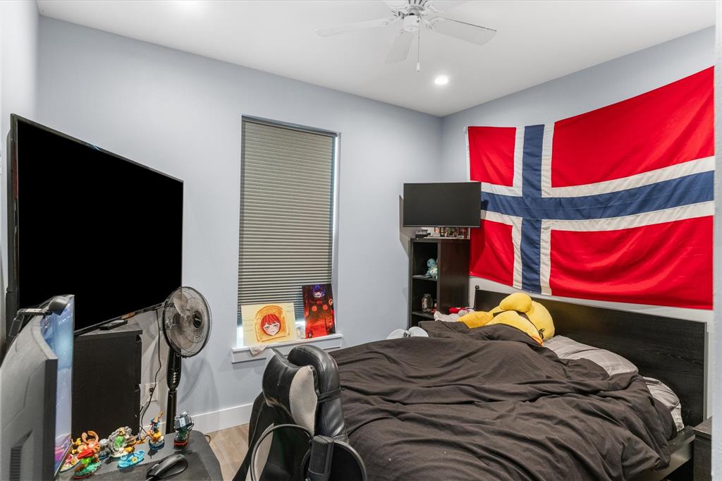 Interior room featuring a ceiling fan with integrated lighting, wood-finish flooring, and a single vertical window with blinds