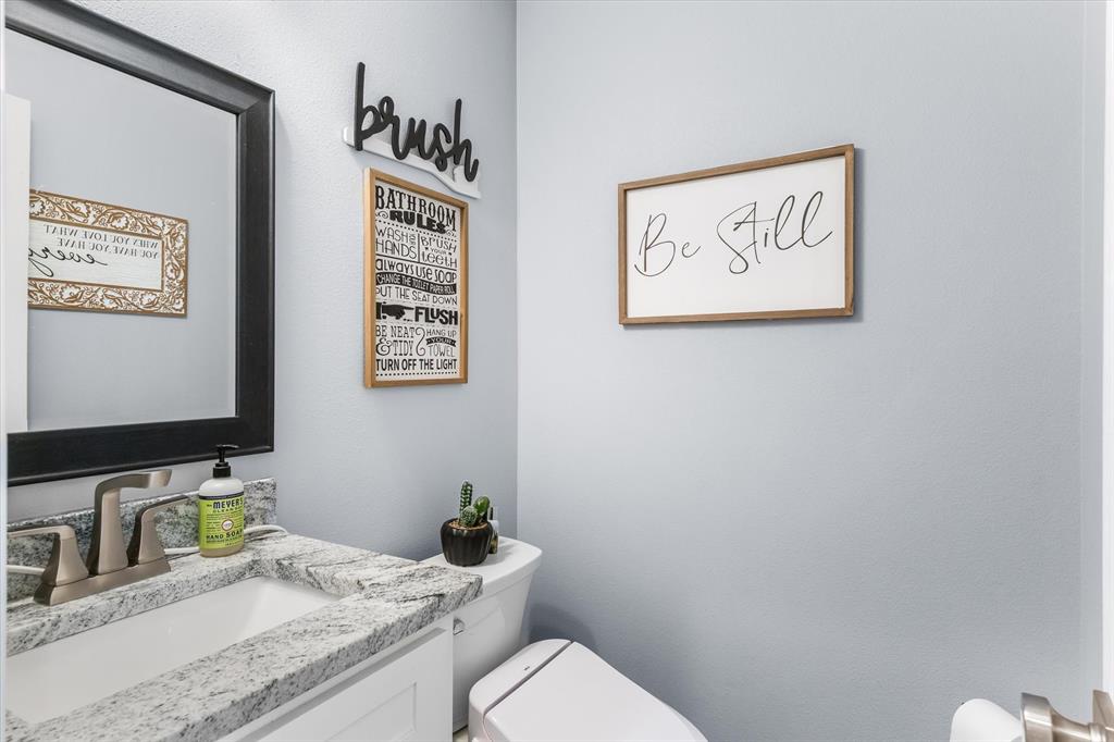 Stone countertop, undermount sink, dual-handle brushed nickel faucet, and framed rectangular mirror