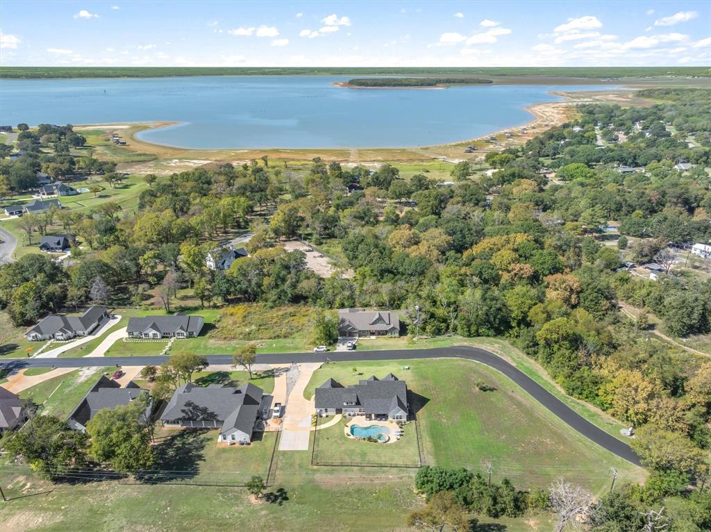Aerial perspective of property featuring an inground swimming pool, asphalt driveway, manicured lawn, and perimeter fencing