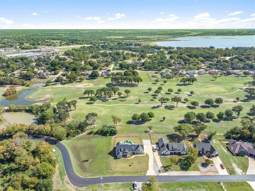 Aerial perspective featuring expansive acreage, a private swimming pool, mature tree canopy, and proximity to a lake and golf course