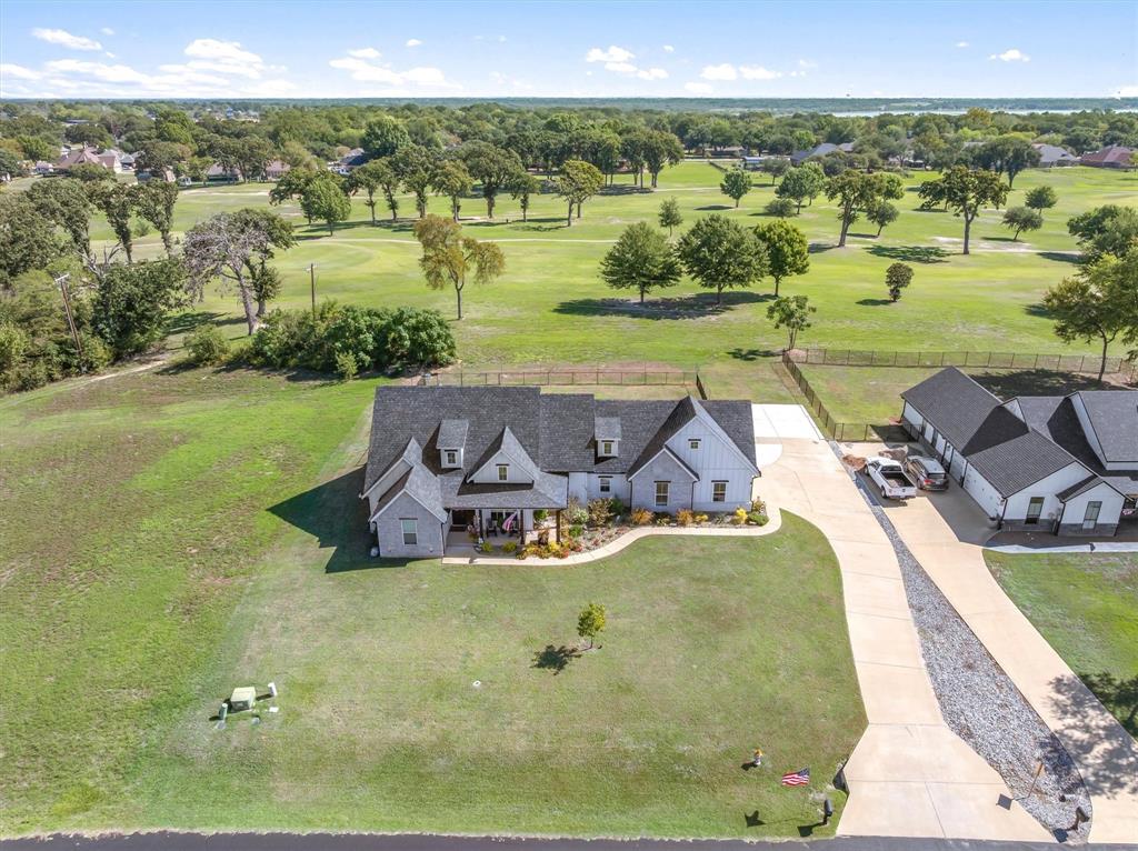 Multi-structure property featuring a gabled roofline, concrete driveway, stone and vertical siding exterior, and expansive acreage Multi-structure property featuring a gabled roofline, concrete driveway, stone and vertical siding exterior, and expansive acreage