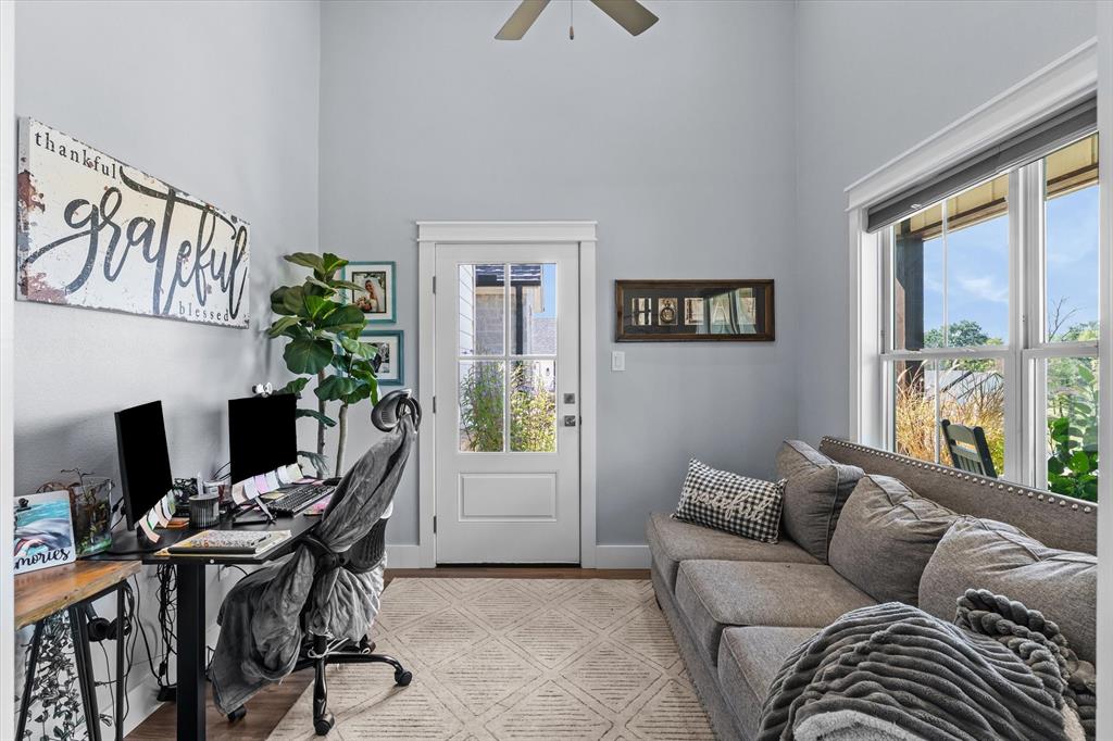 High ceilings, multi-pane glass entry door, large multi-pane windows, and ceiling fan