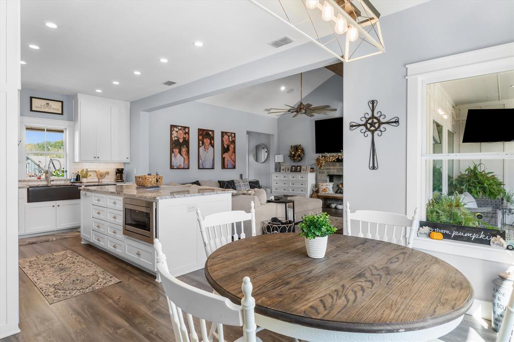 Kitchen featuring white cabinetry, a center island with integrated microwave, farmhouse sink, recessed lighting, and wood-finish flooring