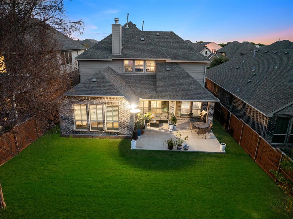Two-story residence featuring a combination brick and siding exterior, expansive backyard with a manicured lawn, concrete patio, and enclosed wood fencing