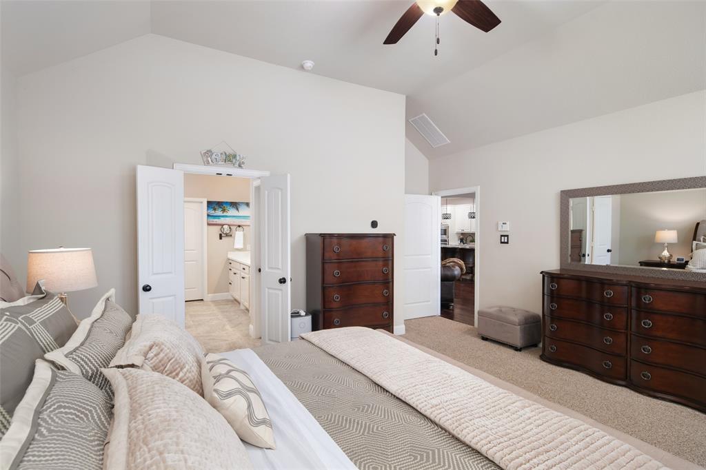 Vaulted ceilings, neutral wall tones, carpeted flooring, and a ceiling fan with integrated lighting