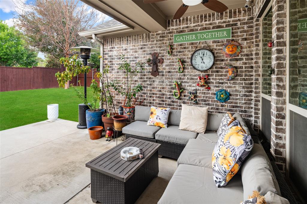 Covered patio featuring a brick facade, concrete flooring, and an integrated ceiling fan
