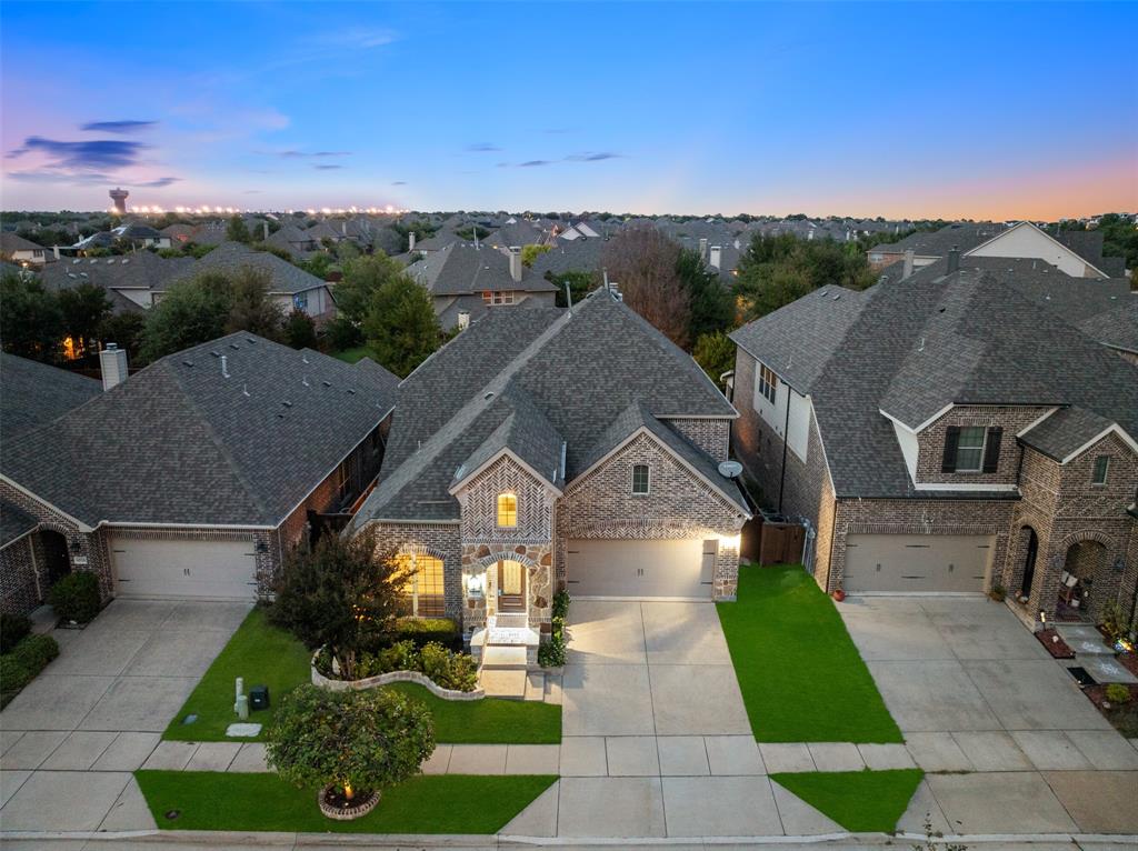 Brick and stone masonry facade with a multi-gabled roofline, concrete driveway, and professional landscaping featuring a curved stone retaining wall