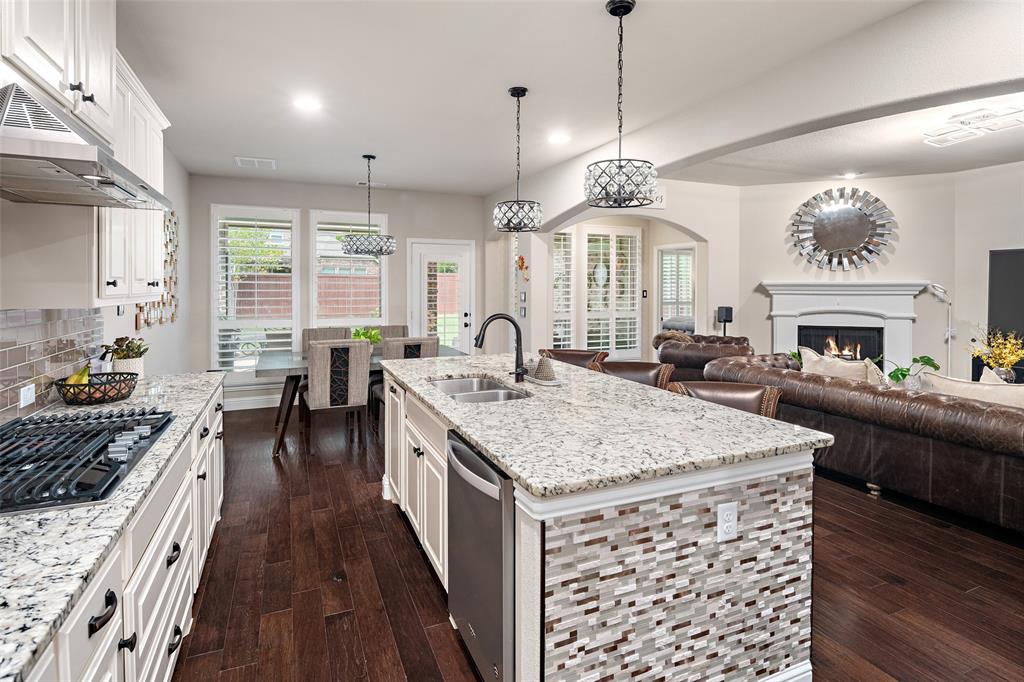 Kitchen featuring a central island with stone countertops, tiled island facade, white cabinetry, gas cooktop, and wood-finish flooring