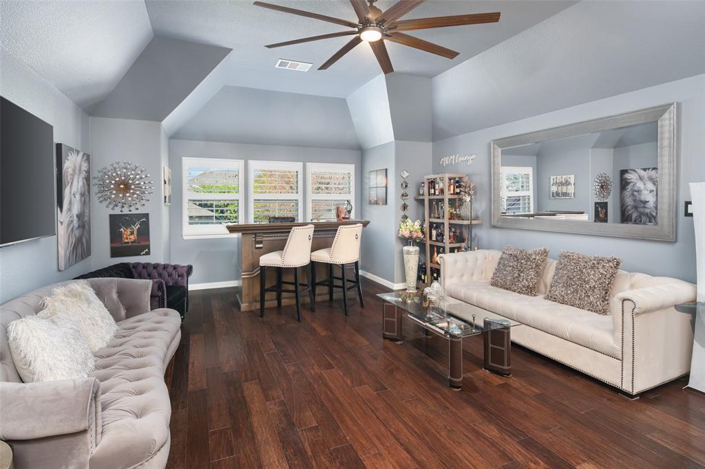 Vaulted ceilings, wood-finish flooring, built-in wet bar, and overhead ceiling fan